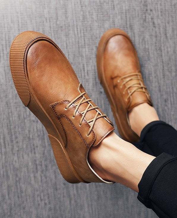 Brown leather shoes worn on a gray textured surface
