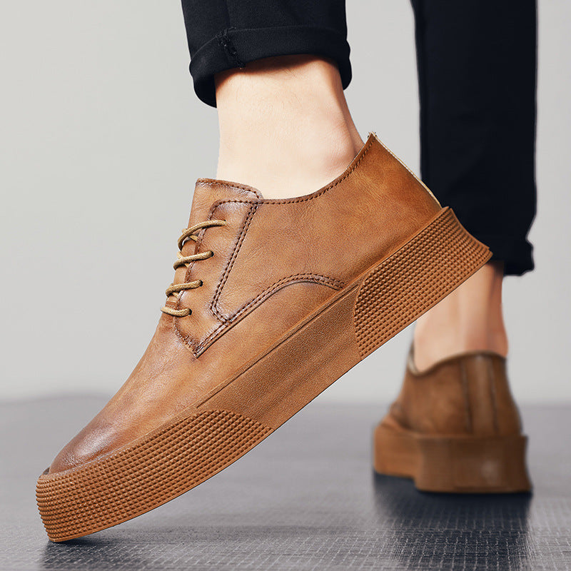 Brown leather shoes worn by a person on a gray background