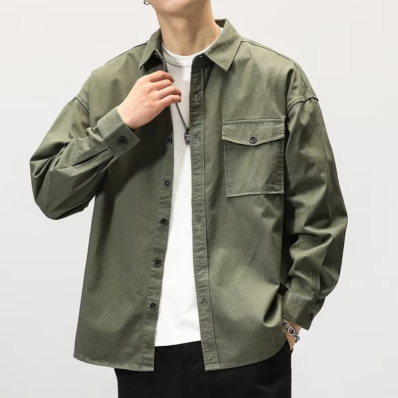 Person wearing a green shirt over a white shirt on a light gray background