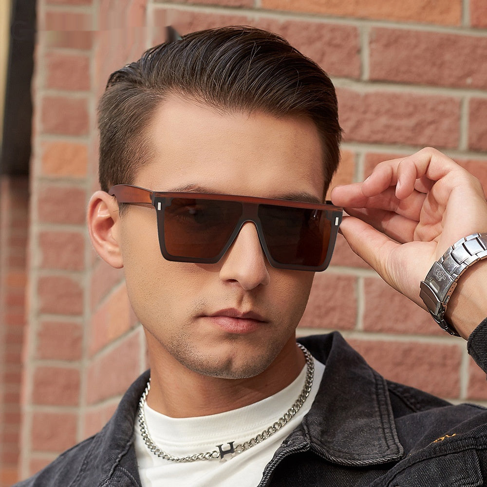 Man adjusting sunglasses in front of a brick wall