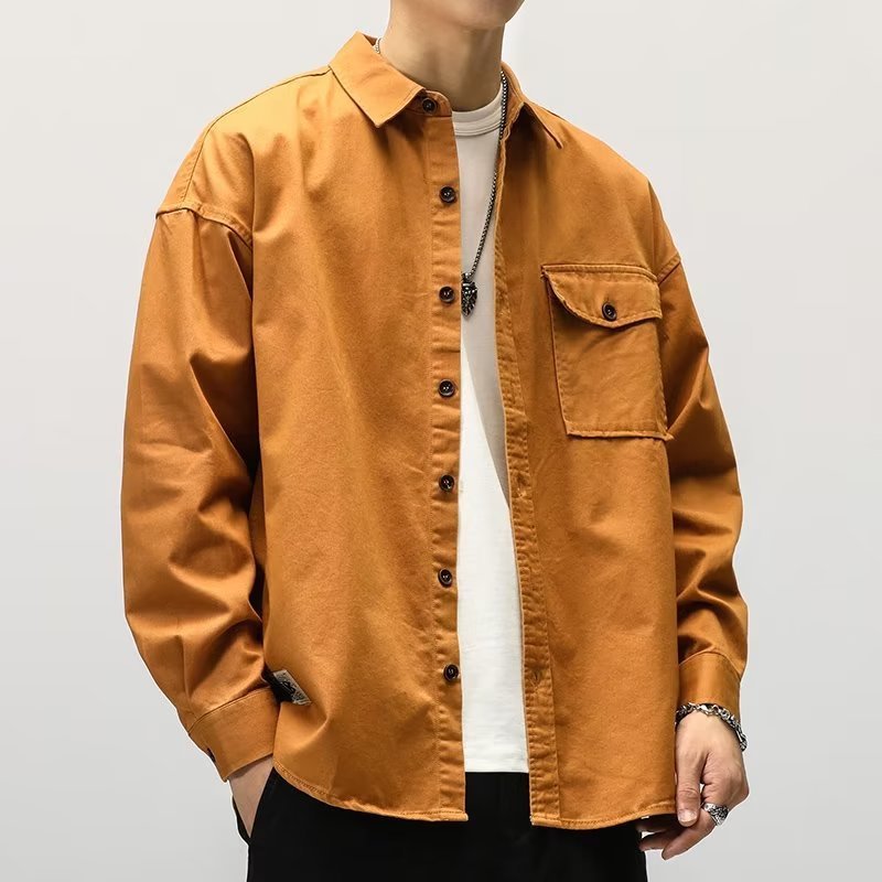 Person wearing a mustard yellow shirt over a white shirt on a plain background